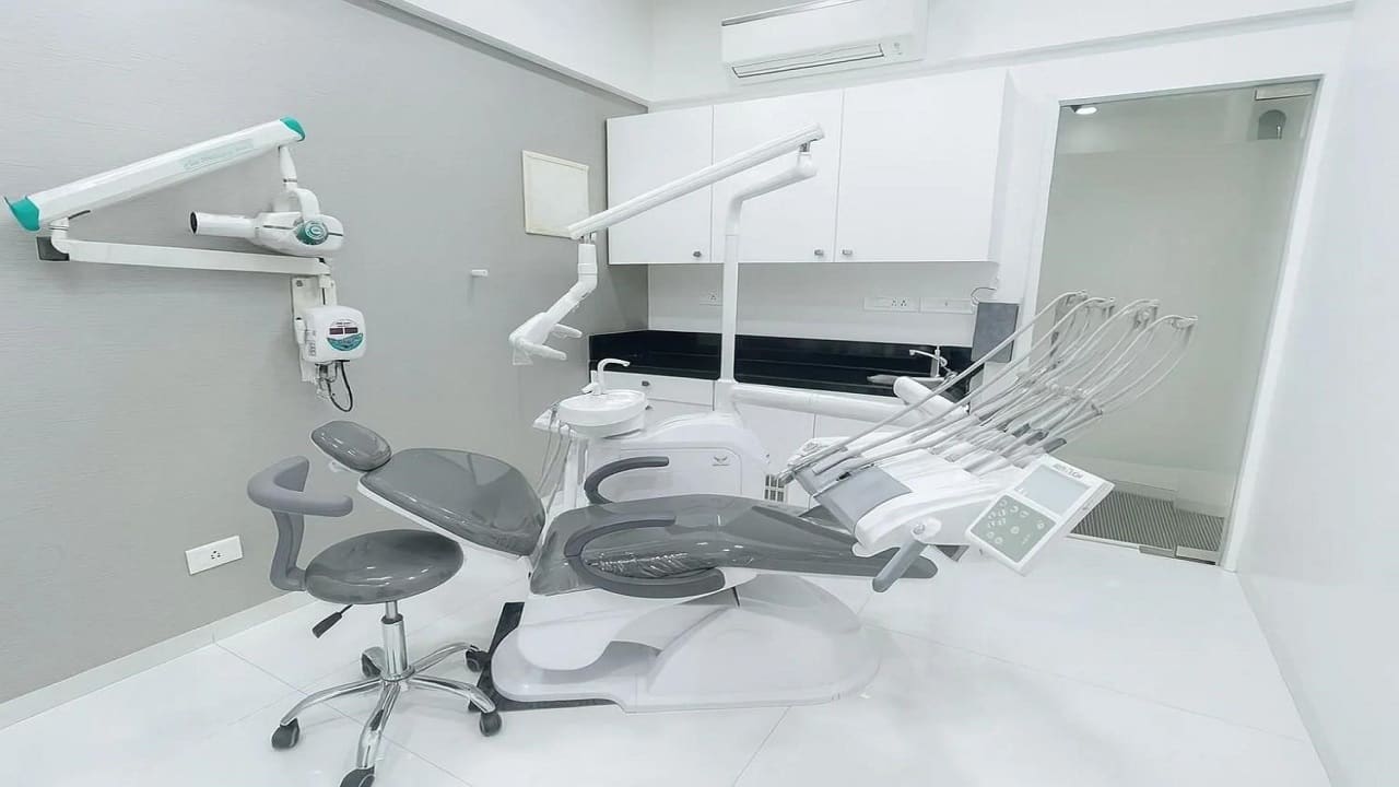 Treatment room with a grey dental chair and wall mounted X-ray unit